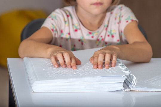 Child tries out Braille on a page with her fingers