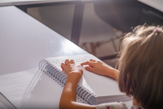 Child's hands on a books page with Braille