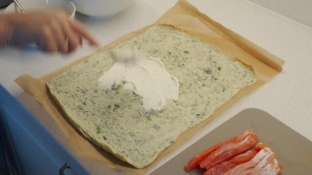 Preparing a roll with soft cream cheese and red fish. Spreading whipped cheese and spice mixture onto saj bread, then top with salmon.