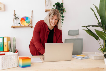 Cheerful blonde boss working with computer in office