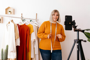 Confident seamstress making online video in atelier