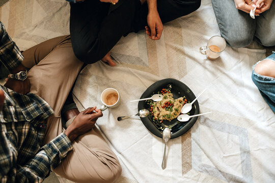 Multiracial students eating upma at the hostel room together.