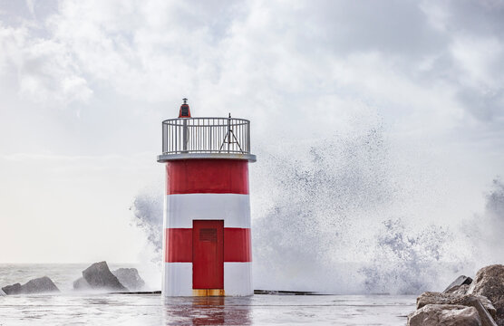 Red and white lighthouse on a stormy day.