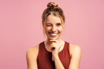 Smiling pretty woman in sportwear winking looking at camera, holding hand on cheek