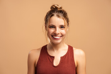 Portrait of sporty young woman in sportwear posing at camera, isolated on beige in studio