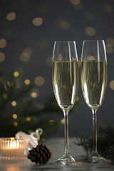 Delicious champagne in glasses and Christmas decor on marble table against blurred lights, closeup