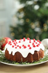 Traditional Christmas cake decorated with red currants and rosemary on wooden table