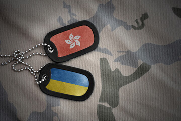 army blank, dog tag with national flag of hong kong and ukraine on the khaki texture background....