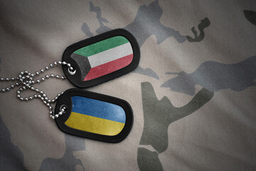 army blank, dog tag with national flag of kuwait and ukraine on the khaki texture background. military concept.