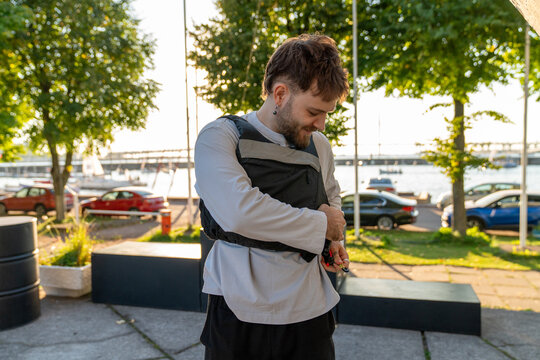 Man fastening life vest outdoors by the waterfront.