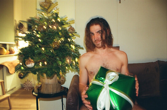 Young man with a Christmas present by the tree