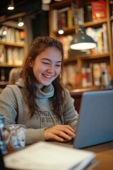 A young woman sitting at a table with a laptop, possibly doing work or studying