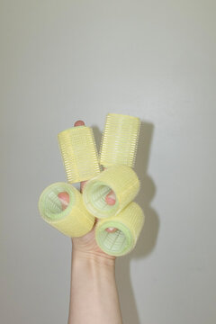 Hand holding yellow beauty hair curlers / hair rollers playful way 