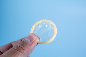 Image of a rolled-up condom on a blue background. Using a condom significantly decreases the risk of gonorrhea, chlamydia, trichomoniasis, hepatitis B, and HIV.