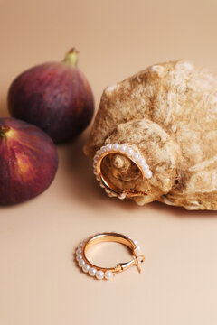 Ring earrings on a textured shell with fresh figs