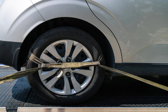 Close of a wheel strapped down on a flatbed tow truck 