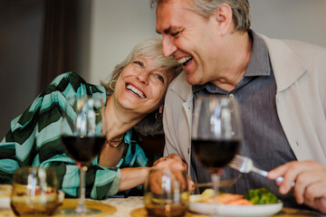 Senior couple laughing and having fun while eating dinner together