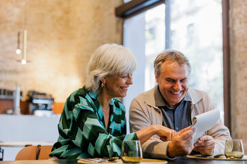 Happy senior couple holding a menu in restaurant