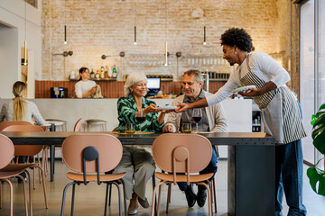 Couple being served food by waiter in restaurant