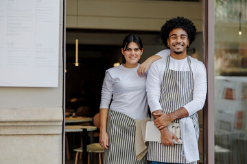 Two smiling workers posing at the entrance of a restaurant
