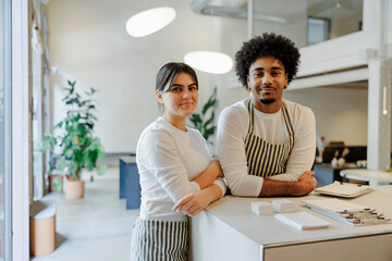 Two confident restaurant workers leaning on a countertop