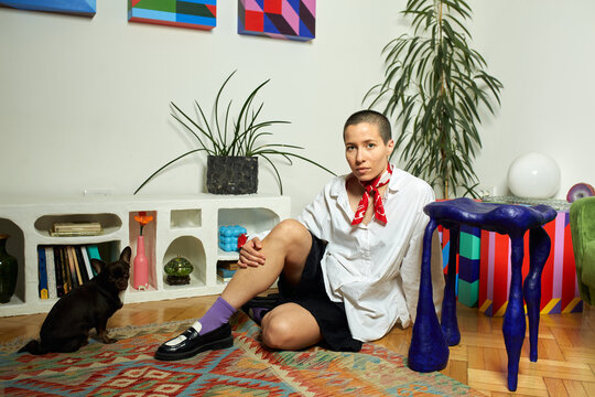 Short-haired woman sits on the floor next to a dog