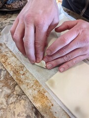 Two hands close up the a gluten free vegan puff pastry dish that is now ready to go into the oven. You can stuff the puff pastry with delicious vegan vegetables. 
