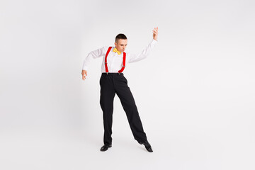 Young gentleman in elegant attire dancing energetically on a white background
