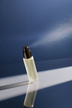 Elegant Perfume Bottle with Spray on Blue Background
