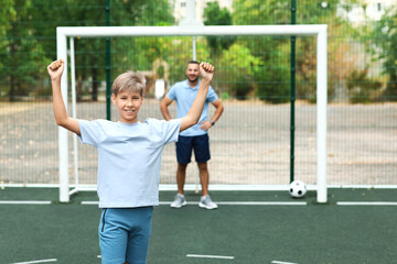 Father and son playing soccer on field