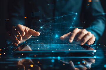 A businessman uses a tablet with a digital graph and network connection on a virtual screen over a dark background. The closeup shows the hands holding a touchpad with data or information technology.