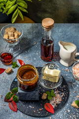 Delicious salted caramel sauce with ingredients on dark background
