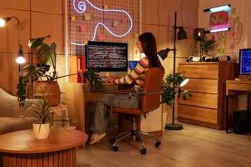 Female programmer working with computer in office at night