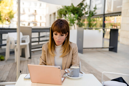 Confident business woman using laptop in a coffee shop.