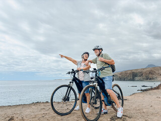 Fototapeta premium Two happy old mature people enjoying and riding bikes together to be fit and healthy outdoors. Active seniors having fun training in nature. Portrait of one old man smiling in a bike trip with wife