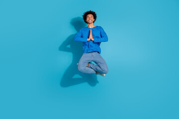 Full body photo of attractive young man jumping meditate dressed stylish clothes isolated on blue...