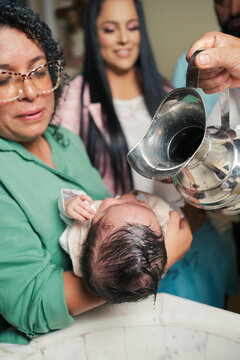Godmother holds her godchild as he is being baptized.