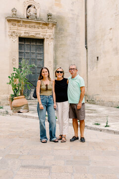 Vacationer posing with her parents in the streets of the city Lecce