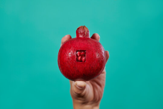 man holds a pomegranate with a rectangular opening 