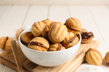 Bowl with sweet walnut shaped cookies with boiled condensed milk on white wooden background