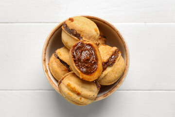 Bowl with sweet walnut shaped cookies with boiled condensed milk on white wooden background
