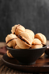 Bowl with sweet walnut shaped cookies with boiled condensed milk on wooden table