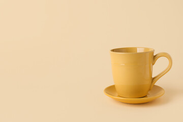 Yellow ceramic empty mug with saucer on beige background