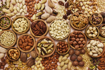 Colorful mix of various nuts: peanut and cashew, hazelnut and almond, pine nuts and walnut; healthy diet snack; vegan food background