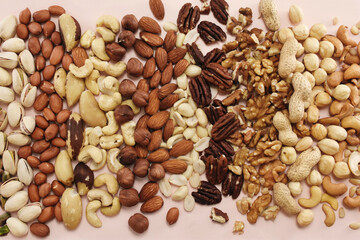 Colorful mix of various nuts: peanut and cashew, hazelnut and almond, pine nuts and walnut; healthy diet snack; vegan food background