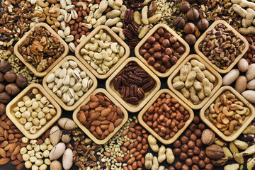 Colorful mix of various nuts: peanut and cashew, hazelnut and almond, pine nuts and walnut; healthy diet snack; vegan food background