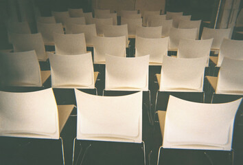 Rows of white chairs under the sunlight. 