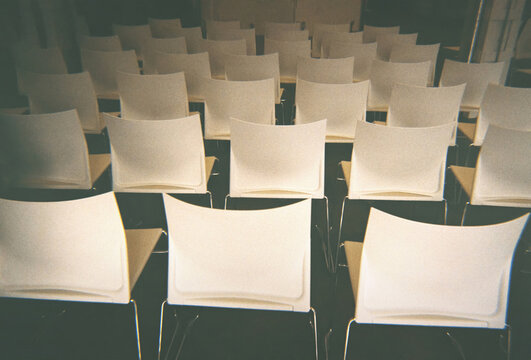 Rows of white chairs under the sunlight. 