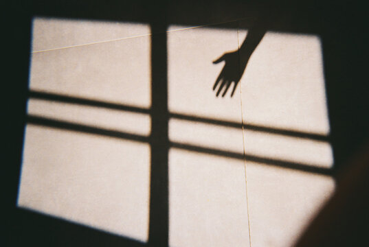 A hand reaching toward sunlight streaming through a window