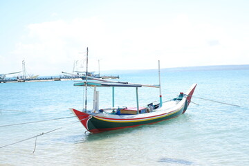 Obraz premium Quiet Beach with Traditional Boat and Clear Blue Waters